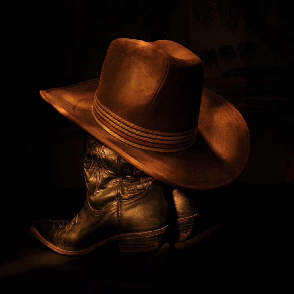 A cowboy hat and boots in the dark.